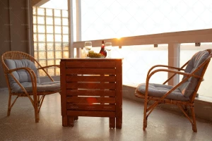 یک بالکن با چند صندلی، یک میز چوبی با نوشیدنی و انگور