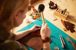 تصویر یک خانم صنعتگر در‎حال ساخت کیف چرمی از زاویه بالا