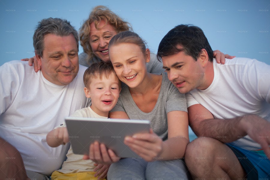 یک خانواده در حال نگاه کردن به تبلت و آی‌پد