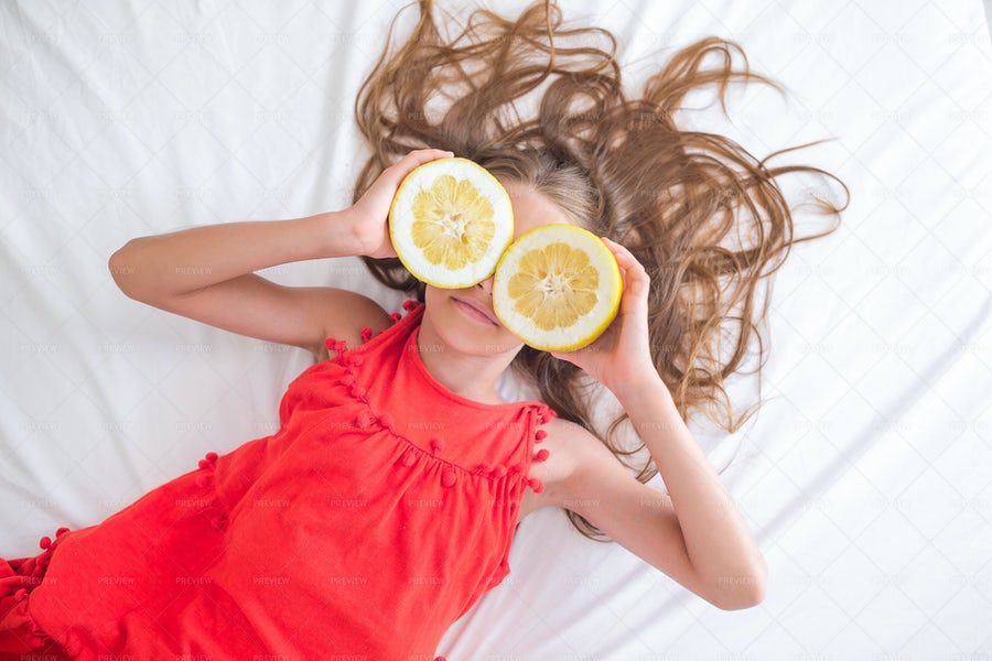 دختر کوچک که چشمانش را با تکه های لیمو پوشانده است