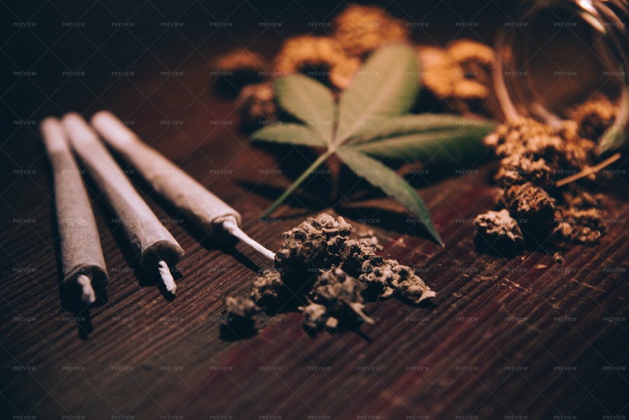 عکس سه سیگار کنار تنباکو بر روی میز چوبی