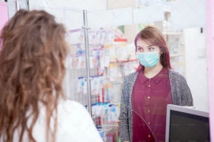 یک مشتری در داروخانه که به خاطر ویروس کرونا ماسک به صورت زده