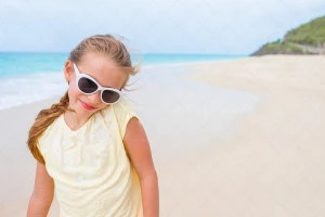 دختر نوجوان عینک دودی به چشم زده و در ساحل راه میرود
