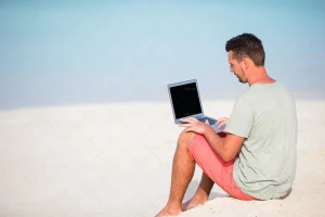 مرد در حال کار با لپ تاپ در ساحل
