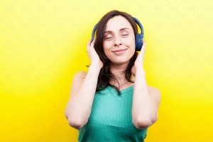 یک خانوم  در حال گوش دادن به موزیک با هدفون با پس زمینه زرد