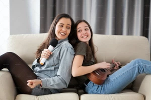 دو خواهر شاد که روی مبل نشسته و آواز می خوانند