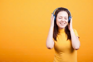 یک خانوم درحال گوش دادن به موزیک با هدفون با پس زمینه زرد