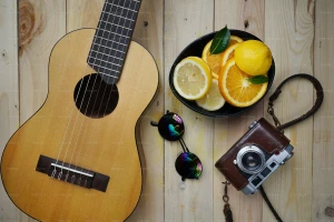 تصویر یک گیتار و دوربین قدیمی روی میز چوبی