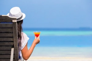 خانومی در حال نوشیدن آبمیوه در ساحل