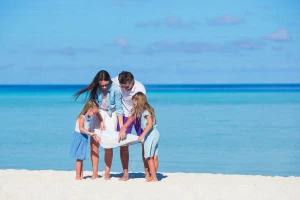 یک خانواده در حال نگاه کردن به نقشه زیر آفتاب ساحل