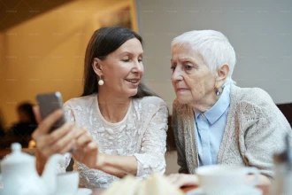 زن میانسال در حال یاد دادن کار با موبایل به دوستش