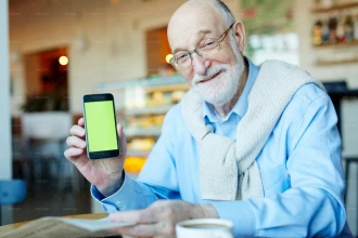 مرد کهنسال در حال نشان دادن تلفن همراه با صفحه نمایش سبز
