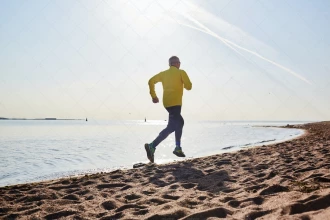 تصویر یک مرد در حال دویدن روی شن های ساحل