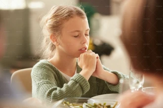 دختری در حال دعا سر میز غذا