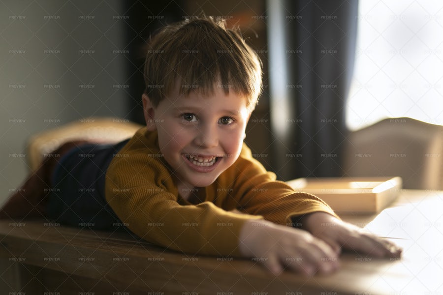 کودک خندان و خوشحال بر‌روی یک میز چوبی